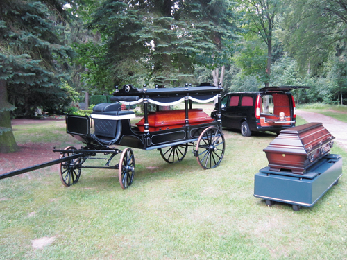Bestattungswagen, -kutsche und Sarg auf dem Friedhof.